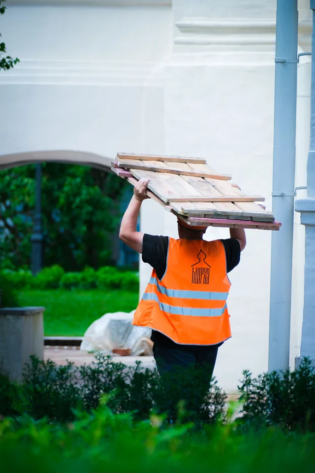 Construction worker carrying lumber outdoors